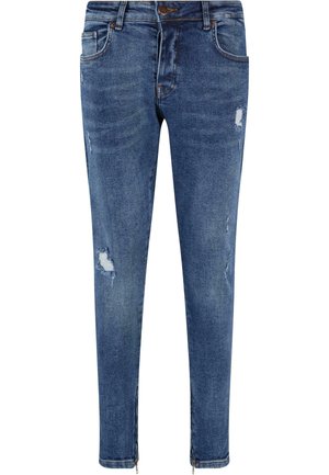 Jeans skinny din denim albastru, cu detalii deteriorate, având buzunare frontale și fermoare la gleznă. Textură netedă și design ajustat.