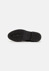 Suela de zapato de goma negra con un patrón texturizado, que presenta profundas ranuras para tracción y un diseño plano sin marcas visibles.
