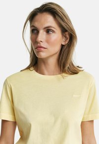 T-shirt met korte mouwen en ronde hals in lichtgeel katoen met een subtiel logo op de borst. Soepele textuur en een relaxte pasvorm.