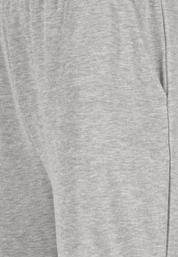 Graue Sweatpants aus weichem Material, mit elastischem Bund, seitlichen Taschen und einer glatten Textur. Dezentes Logo-Detail sichtbar.