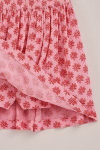 Roosa kangas kogutud tekstuuri ja punase lillemustriga, kus on näha kihiline äär nähtavate õmblusdetailidega.