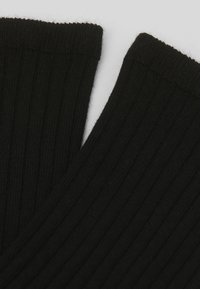 Sort ribbet stof med en blød tekstur, der har let rullede kanter og en glat finish, som viser et ensartet mønster gennemgående.