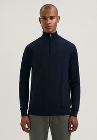 Maglione zip-up blu navy realizzato in materiale liscio, dotato di un colletto alto, maniche lunghe e polsini e orlo a costine.