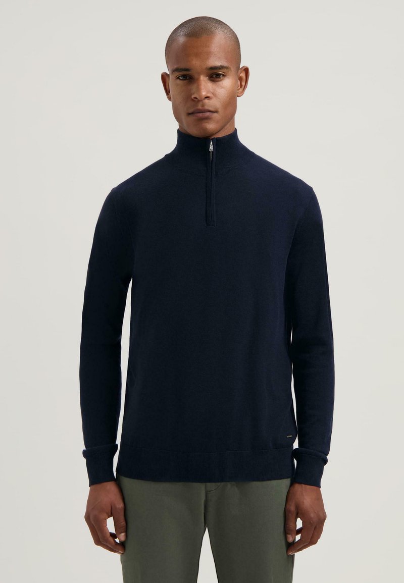 Maglione zip-up blu navy realizzato in materiale liscio, dotato di un colletto alto, maniche lunghe e polsini e orlo a costine.