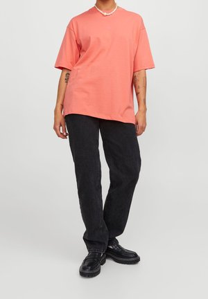 Světle korálové oversized tričko s kulatým výstřihem, v kombinaci s černými širokými džínami a masivními černými botami, vyrobené z hladké bavlny.