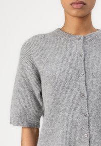 Gray short-sleeve cardigan made of soft, textured knit fabric. Features a round neck, button closure, and subtle ribbing pattern.