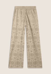 Pantalons beige à jambes larges avec une taille smockée, présentant un motif découpé complexe de hexagones et de formes florales sur tout le tissu.