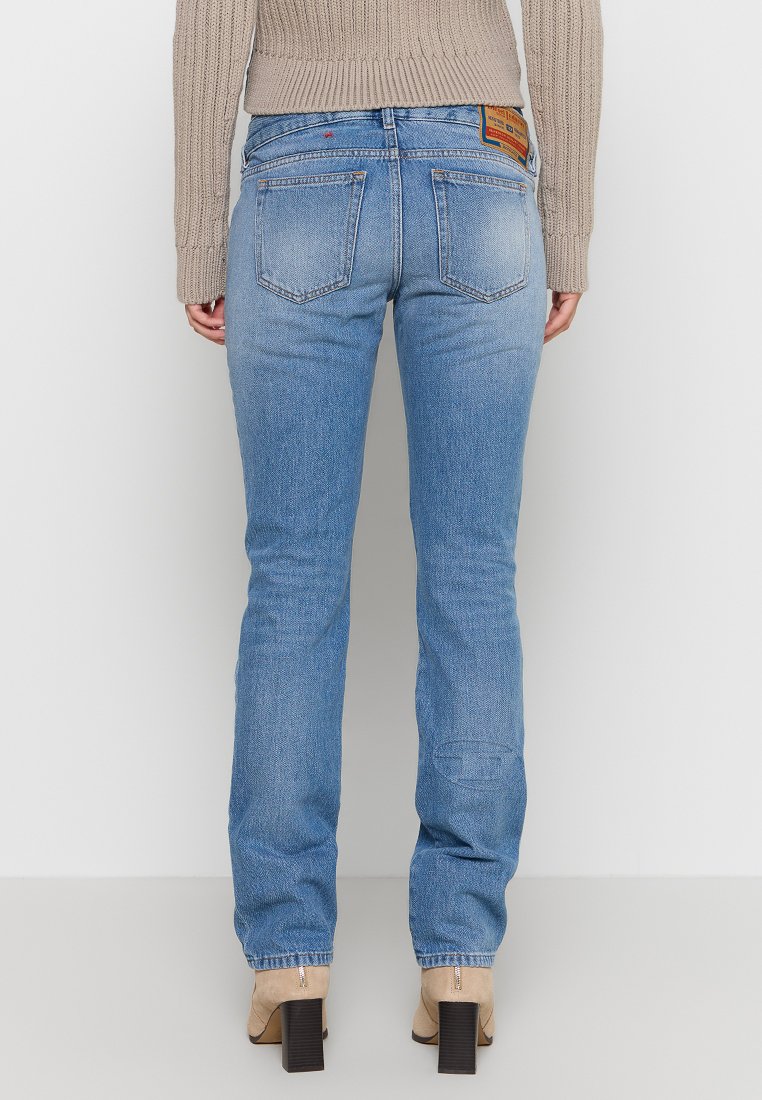 Jeans in denim azzurro chiaro con taglio dritto, cinque tasche e un'etichetta in cuoio sul retro. Il tessuto presenta una leggera scoloritura e dei segni di usura.