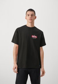 Sort bomulds T-shirt med korte ærmer, rund hals, med et rødt og hvidt "ZOYORK" logo på venstre bryst. Tekstureret stof, afslappet fit.