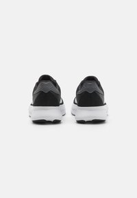Black athletic shoes with gray accents, mesh upper, padded heel, and white sole featuring a textured finish and ridged black tread.