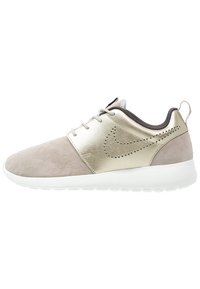 Lightweight sneaker featuring a suede upper in taupe and metallic gold accents, with a white rubber sole and minimalistic design.