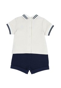 T-shirt blanc à manches courtes avec bord et col bleu marine, associé à un short bleu marine à revers.