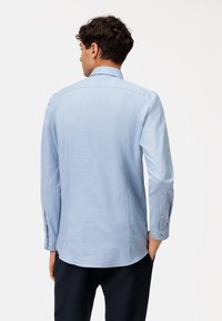 Hellblaues, langärmeliges Herrenhemd mit klassischen Kragen und abgerundetem Saum. Glattes Gewebe mit feiner Textur. Mit Knöpfen verstellbare Manschetten.