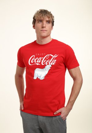 Red cotton t-shirt featuring "ENJOY COCA-COLA" text and a white polar bear graphic on the front. Short sleeves, classic crew neck design.
