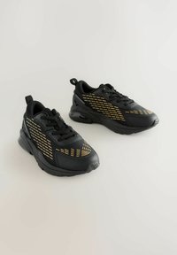 Schwarze Sportschuhe mit gelben Akzenten, aus Mesh-Material, mit strukturiertem Design sowie gepolstertem Schaft und Zunge. Mit einer strapazierfähigen Gummisohle.