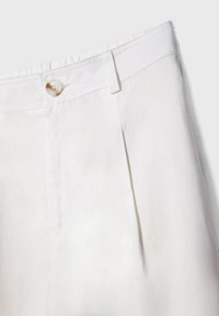 Pantalon blanc plissé en tissu léger, doté d'une texture lisse et d'une fermeture à bouton unique à la taille.