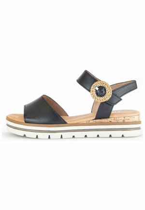 Sandale en cuir noir à bout ouvert, semelle style liège, fond blanc et un accent tressé rond sur la bride.