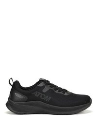 Zapato deportivo negro con parte superior de malla transpirable, suela texturizada y una marca sutil. El diseño incluye una punta redondeada y cierre con cordones.