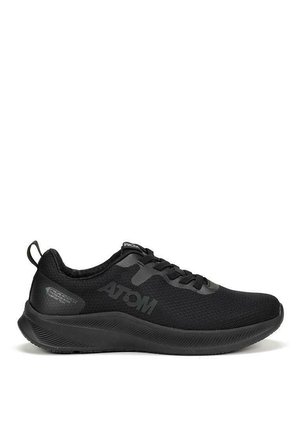 Zapato deportivo negro con parte superior de malla transpirable, suela texturizada y una marca sutil. El diseño incluye una punta redondeada y cierre con cordones.