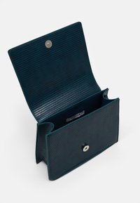 Portfel z tealowej skóry o fakturowanej powierzchni, wyposażony w zapięcie zatrzaskowe i wewnętrzną przegrodę z metką. Widok od środka pokazuje dwie kieszenie.