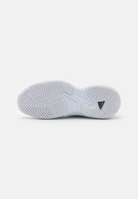 Talpa de pantof sport albă cu un model în zig-zag, textură netedă și logo negru. Prezintă un sistem de torsiune pentru stabilitate.