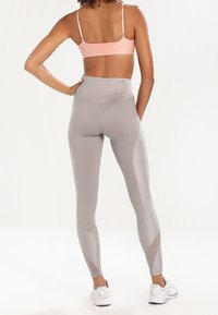 Leggings a vita alta in grigio chiaro, con una cinturina elastica testurizzata e pannelli in rete per traspirabilità e comfort.