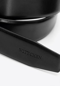 Czarny skórzany pasek o gładkiej teksturze, z wytłoczonym logo "WITTCHEN" oraz prostym, eleganckim wzornictwem.
