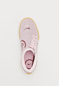 Light pink athletic shoe with a glossy synthetic upper, contrasting darker pink swoosh logo, and beige rubber outsole; flat laces.