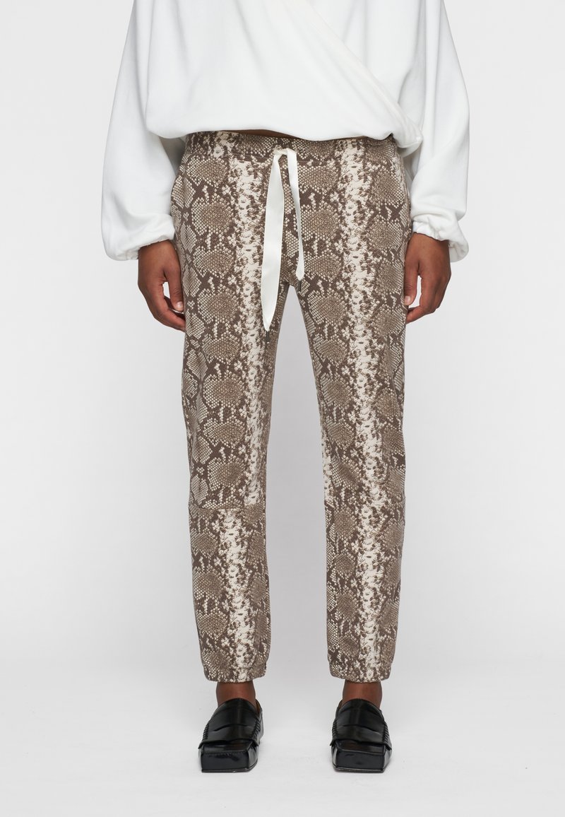 Bruine en witte joggers met slangenprint, voorzien van elastische manchetten en een trekkoord in de taille. Zacht materiaal met getextureerde patronen.