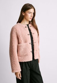 Rosa Kunstpelzjacke mit lockerer Passform, runder Halslinie und vorderen Druckknopfverschlüssen. Verfügt über eine aufgesetzte Tasche und strukturierten Stoff.