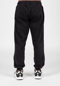 Zwarte joggingbroek van katoen, met een elastische tailleband en boorden. Glad oppervlak met zijnaad en een klein logootje.