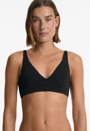 Bralette wireless nera con scollatura a V profonda, spalline larghe e dettagli delle cuciture; texture liscia e design minimalista.