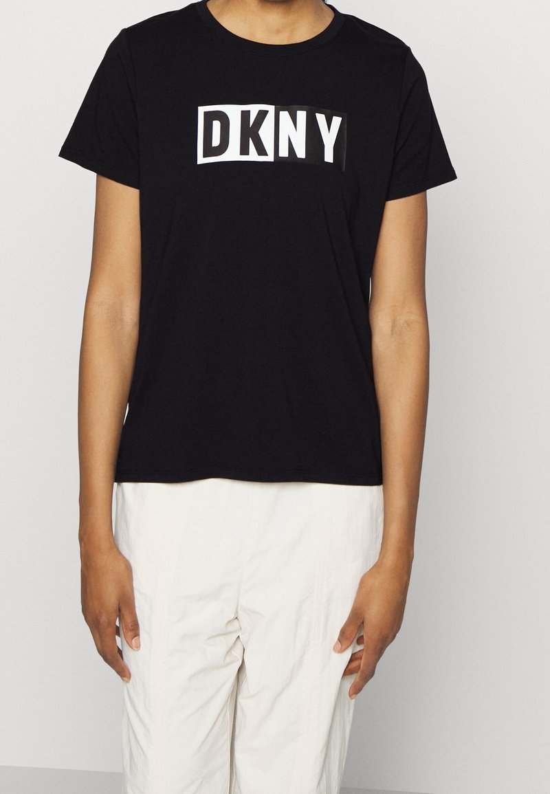 Czarny bawełniany t-shirt z białym logo "DKNY" w prostokątnym wzorze na przodzie. Krótkie rękawy i okrągły dekolt.