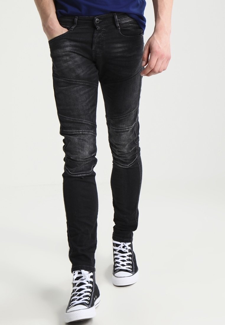 Mustat farkut, joissa on kapea malli, ja joissa on kulunut pinta sekä paneelitiedot jaloissa. Yhdistetty mustiin lenkkareihin.