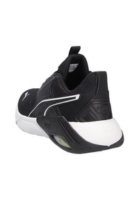 Schwarzer Sportschuh mit strukturiertem Obermaterial, weißer Sohle, auffälliger Fersenkonstruktion und einem kleinen grünen Akzent im Sohlen-Design.
