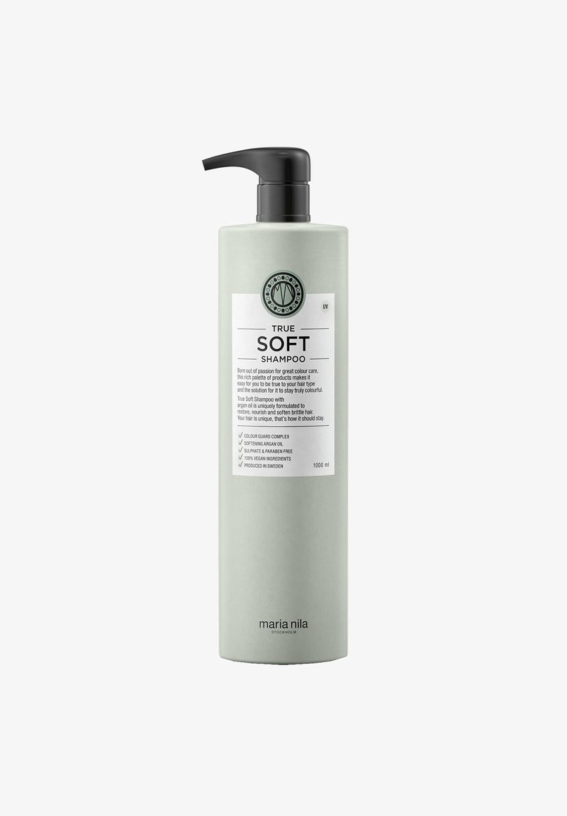 Groene plastic fles met een zwarte pomp, gelabeld "True Soft Shampoo." Bevat een circulair logo, witte tekst en opsommingstekens. 1000 ml.