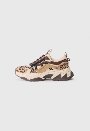Masywne sneakersy z akcentami w panterkę i tygrysa, w beżowych i brązowych odcieniach, z nakrapianą podeszwą i czarnymi oczkami na sznurówki, oznaczone marką Steve Madden.