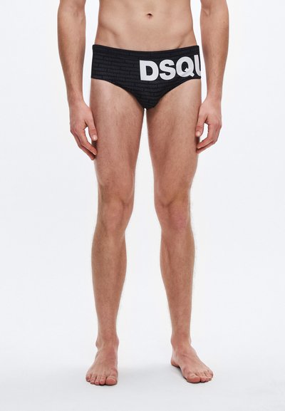 Slip de bain noir avec une coupe haute et un logo blanc audacieux "DSQUARED2". Confectionné en tissu stretch à la texture lisse.