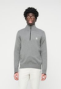 Grauer Reißverschluss-Pullover mit hohem Kragen, aus strukturiertem Stoff gefertigt, mit kleinem Logo auf der linken Brust und gerippten Bündchen und Saum.