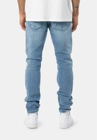 Jeans in denim azzurro chiaro con un taglio slim, dotati di due tasche posteriori e un leggero effetto sbiadito. Abbinati a sneakers bianche, per un look casual.