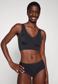 Black seamless bralette with wide straps and V-neck design, paired with matching high-waisted briefs. Smooth texture, comfortable fit.