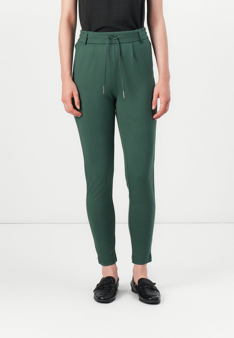 Pantaloni sportivi verdi, aderenti, con vita elastica, cordino e finiture in metallo. Texture liscia, gambe affusolate e tasche laterali.