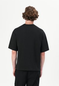 Sort bomulds T-shirt med korte ærmer, rund hals og en afslappet pasform. Glat tekstur uden synlige logoer eller mønstre.