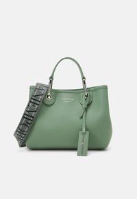 Zielona torba na ramię z fakturowanej skóry z dwoma górnymi uchwytami, srebrnymi okuciami oraz wzorzystym odpinanym paskiem. Posiada oznaczoną metkę bagażową.