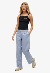 Czarny top na ramiączkach z koronkowym wykończeniem, z białym logo "Superdry Boston"; jasnoniebieskie luźne spodnie w paski z elastycznym paskiem.
