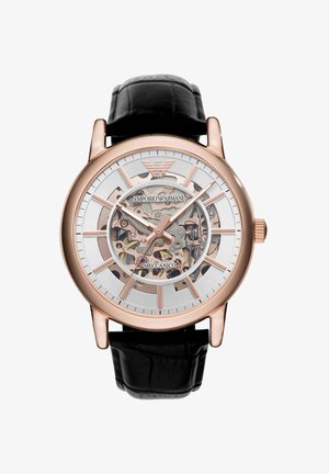Montre mécanique squelette ton or rose avec bracelet en cuir noir, engrenages apparents et logo Emporio Armani sur le cadran.