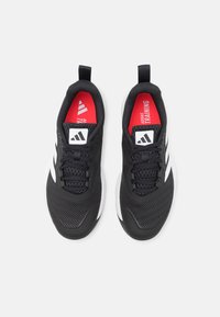 Fekete sportcipők fehér csíkokkal, hálós felsőrész és gumitalp. Jellemzője a piros talpbetét, amelyen az "ADIDAS TRAINING" felirat található.