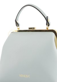 Sac à main en cuir bleu clair avec une armature en métal doré, une poignée courte et un logo "Venezia" embossé à la base. Texture lisse et forme structurée.