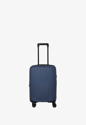 Valise de cabine rigide de taille cabine en bleu foncé avec texture à rainures verticales, matériel noir, poignée télescopique et quatre roues.