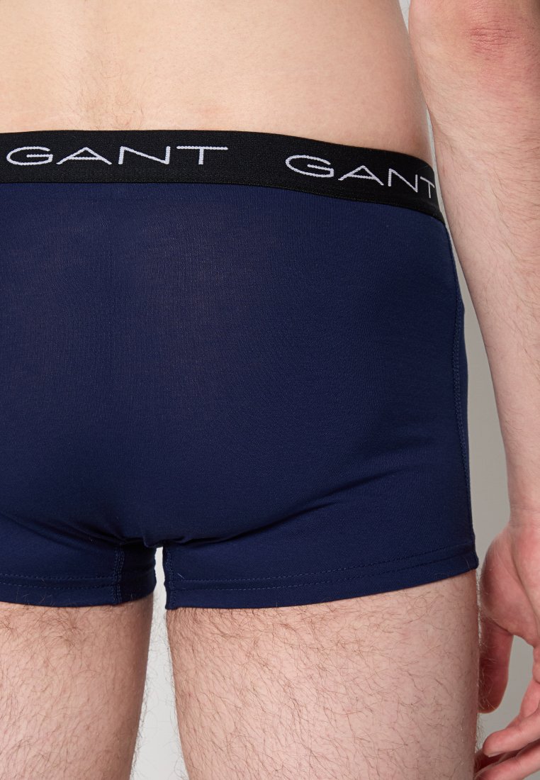 Uomo che indossa boxer blu navy con cintura nera e logo "GANT" bianco, mostrato da dietro all'altezza della vita e delle cosce superiori.